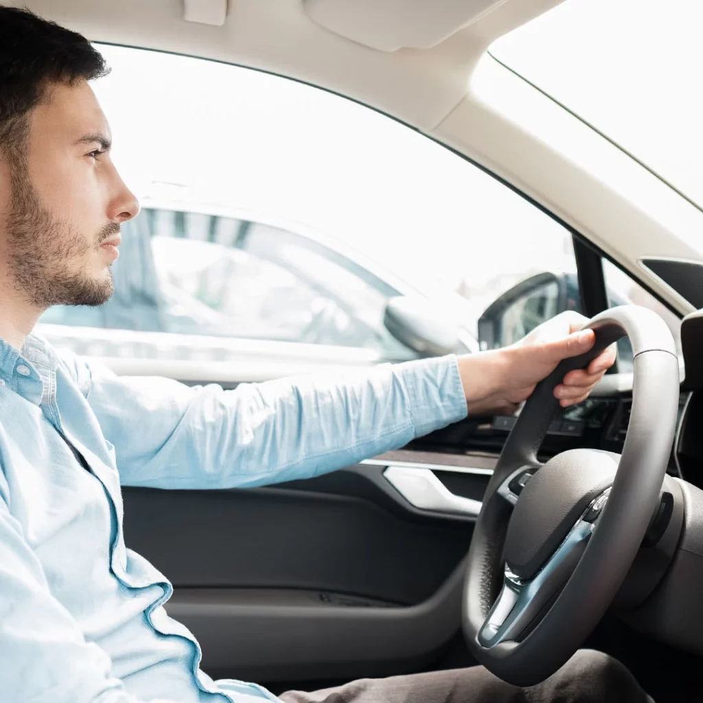 Man in a car, left hand on stirring wheel