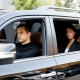 Side view of a luxury SUV vehicle with a male driver and a female passenger inside.