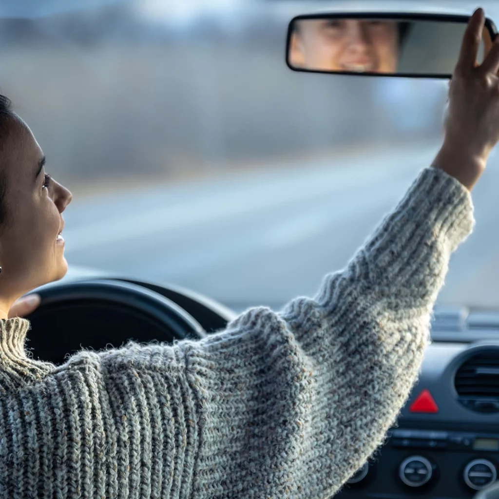 Woman in a car, looking at her rear mirror